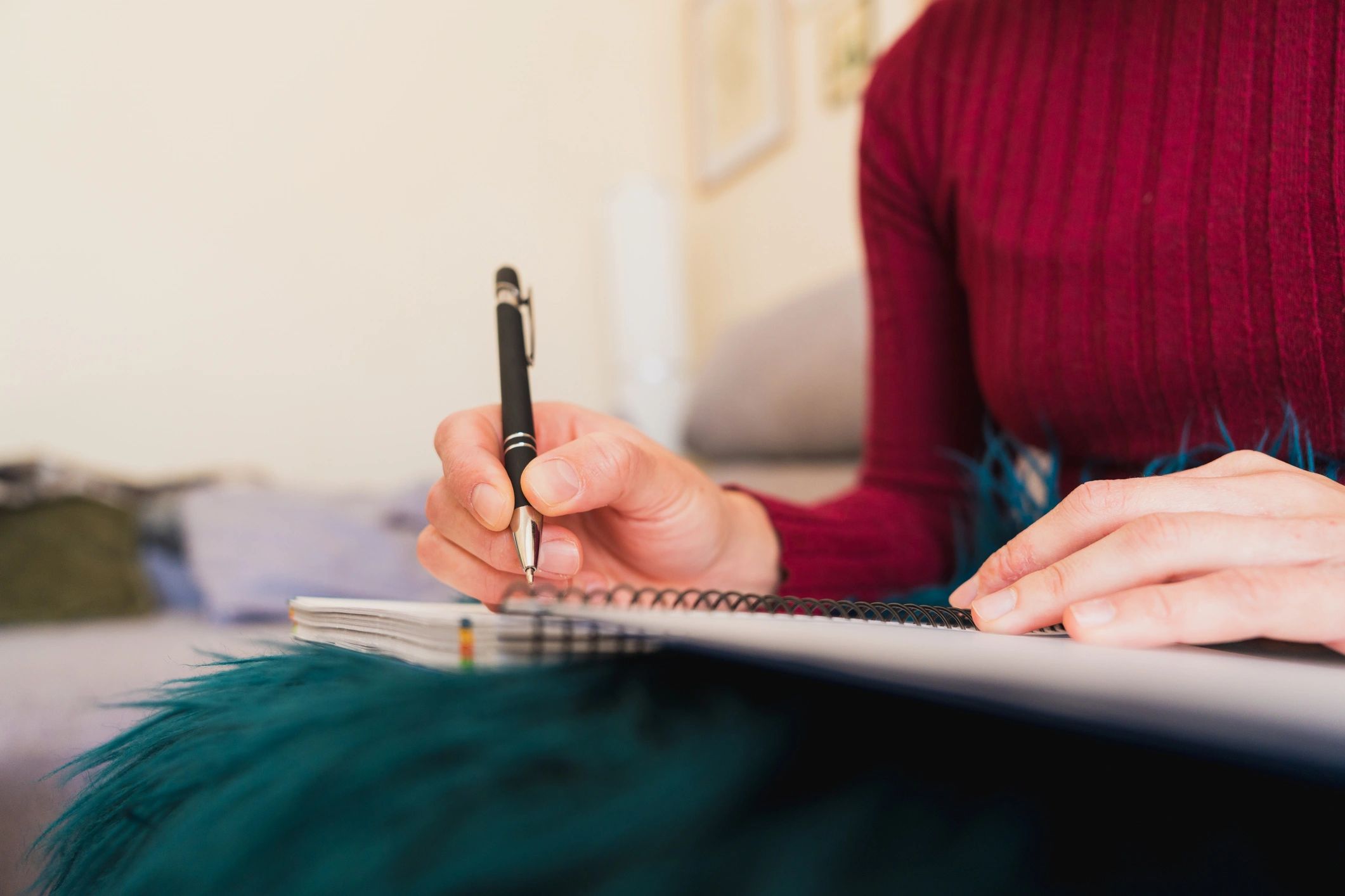 Woman writing notes in notebook at home